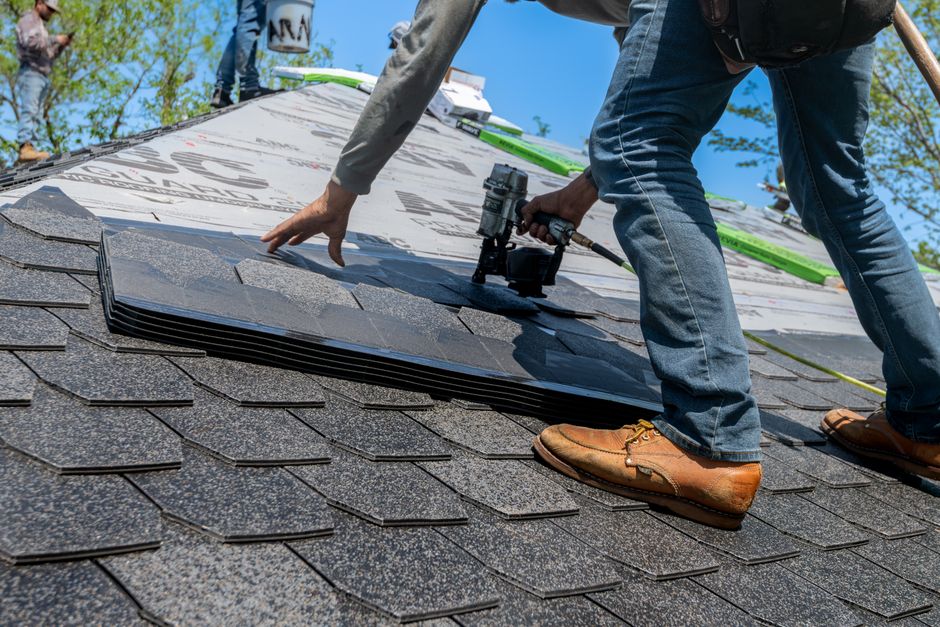 Professional roofer installing asphalt shingles on new roof