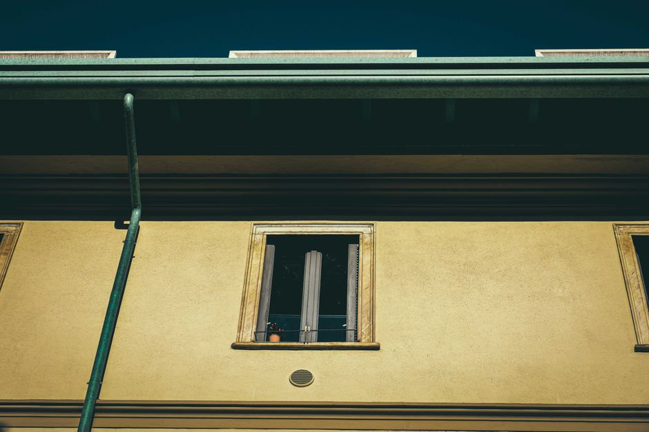 Old residential house facade with gutters and roofline detail in sunlight